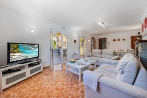 ein Wohnzimmer mit einem Sofa und einem TV in der Unterkunft Villa Ocaso by JS Villas in Port de Pollença