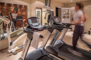 a woman walking through a gym with cardio machines at Poseidon of Paros Hotel & Spa in Chrissi Akti