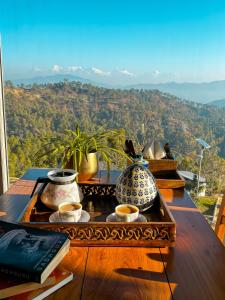 a table with vases on it with a view of a mountain at Shivoham Himalayan Resort in Almora