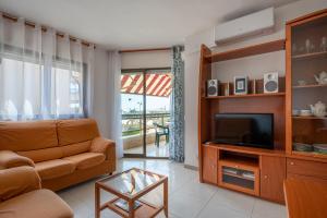 a living room with a couch and a television at AT058 Les Dunes in Torredembarra
