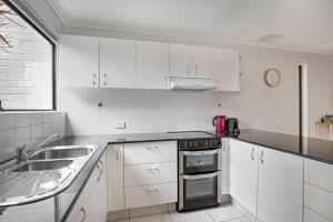 a kitchen with white cabinets and a sink at Woodside Townhouse Peregian Beach in Peregian Beach