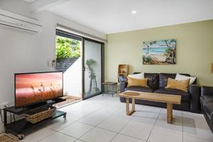 a living room with a couch and a flat screen tv at Woodside Townhouse Peregian Beach in Peregian Beach