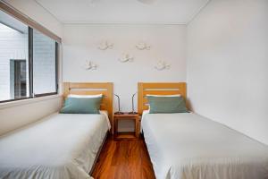 two twin beds in a room with a window at Woodside Townhouse Peregian Beach in Peregian Beach