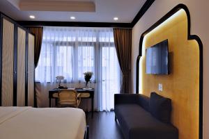 a hotel room with a bed and a desk and a television at Maison Song Anh in Ho Chi Minh City