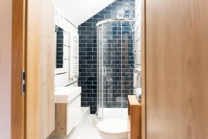bagno con servizi igienici e parete di piastrelle nere. di Apartament w stylu Loft a Spała