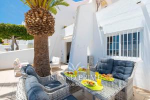 a patio with a table and chairs and a palm tree at Seaviews 2x Bedroom Apartment in Sand Club Complex in San Miguel de Abona