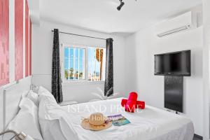 1 dormitorio con 1 cama blanca y TV en Seaviews 2x Bedroom Apartment in Sand Club Complex en San Miguel de Abona