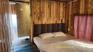 a bedroom with a bed in a room with wooden walls at Vừng Homestay - Taxua in Bắc Yên