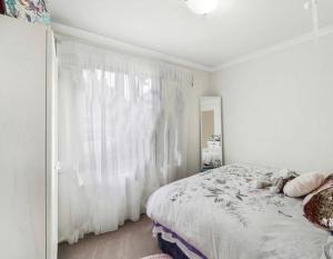 a white bedroom with a bed and a window at The “Pretty Beach House” in Perth