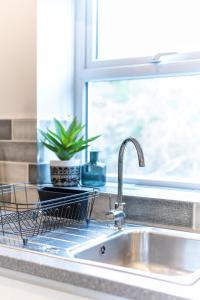 a kitchen sink with a dish drying rack next to a window at Kandaka-Peaceful House in Roundhay