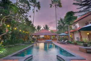 a swimming pool in a backyard with a gazebo at Artini Bisma Ubud Hotel in Ubud