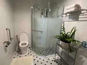 a bathroom with a shower and a toilet with a glass door at Cozycomo Bangkok in Bangkok