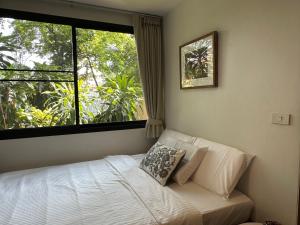 a bedroom with a bed and a large window at Cozycomo Bangkok in Bangkok