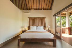 a bedroom with a bed and a large window at Artini Bisma Ubud Hotel in Ubud
