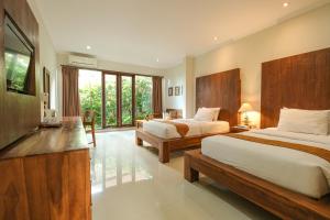 um quarto de hotel com duas camas e uma televisão em Artini Bisma Ubud Hotel em Ubud