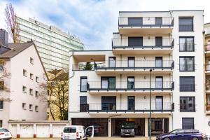 a white building with cars parked in front of it at Sleep Inn Medienhafen Suites in Düsseldorf