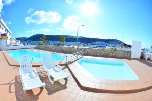 two chairs and a swimming pool on a building at Apartamentos LIVVO Puerto Bello in Puerto Rico de Gran Canaria