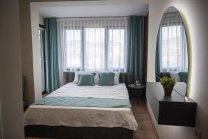 a bedroom with a bed with green curtains and a window at BEST APARTMENTS in Bitola