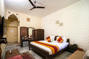 a bedroom with a bed and a ceiling fan at Hotel Chandrawati Palace in Ābu Road