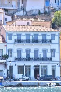 un edificio bianco con auto parcheggiate di fronte all'acqua di Leonidas Hotel a Gythio