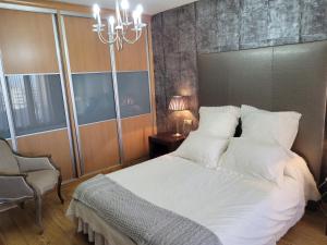 sypialnia z białym łóżkiem i żyrandolem w obiekcie Privada Confort Granada w Grenadzie