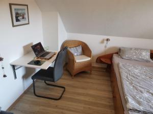 a bedroom with a bed and a desk with a laptop at "Domicil" Abendsonne in Dahme