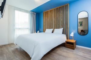 sypialnia z dużym białym łóżkiem i niebieską ścianą w obiekcie Aparthotel Adagio Montpellier Centre Comedie w Montpellier