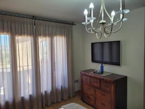 a living room with a television on a dresser with a chandelier at Privada Confort Granada in Granada