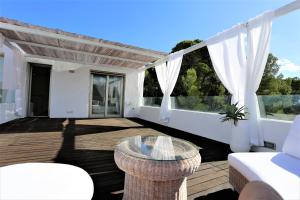 a patio with a glass table and white curtains at Modern Villa Montecristo in Montecristo