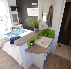 ein kleines Bad mit einem Waschbecken und einem Bett in der Unterkunft Camping Paradis Le Grand' R in La Faute-sur-Mer