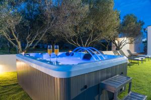 una bañera de hidromasaje en un patio con 2 copas de vino en Villa Grioni, beach front villa with jacuzzi, en Novalja