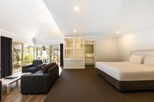 a bedroom with a bed and a couch and chairs at Bayview Geographe Resort Busselton in Busselton