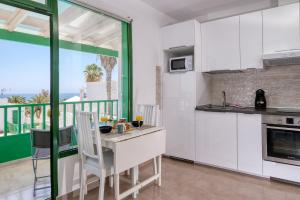 a kitchen with white cabinets and a table with chairs at Suite princesa teguise vista al mar in Puerto del Carmen