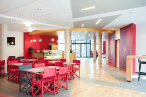 une salle à manger avec des chaises et des tables rouges dans l'établissement Aparthotel Adagio Montpellier Centre Comedie, à Montpellier