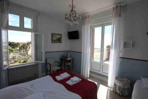 1 dormitorio con 1 cama, 2 ventanas y lámpara de araña en Villa les Dunes, en Saint-Jean-le-Thomas