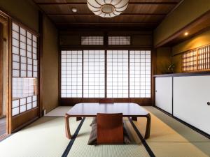 a room with a table and a chair and windows at Nipponia Izumo Hirata Cotton Road in Izumo