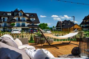 a hammock on a deck with a house at Apartament L 313 widok na góry Sun & Snow Resorts BASEN BALIA BAWIALNIA in Białka Tatrzańska