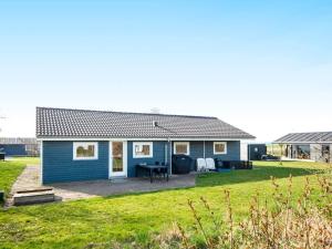 ein blaues Haus mit einer Terrasse und einem Rasenhof in der Unterkunft 12 person holiday home in Vinderup in Vinderup