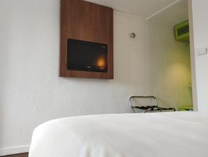 een kamer met een bed en een tv aan de muur bij Noemys ARLES in Arles
