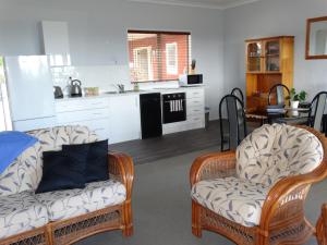 a living room with two chairs and a kitchen at Kauri Lodge Karapiro in Karapiro