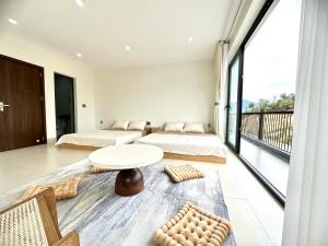 a bedroom with two beds and a table and a balcony at Mỡ Villa Cao Bằng in Cao Bằng
