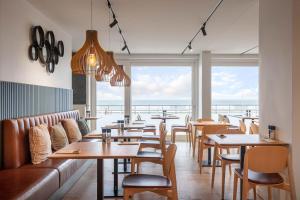 a restaurant with tables and chairs and a view of the ocean at C-Hotels Excelsior in Middelkerke