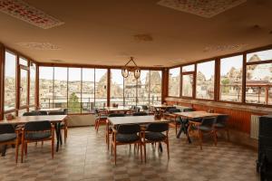 Un restaurante con mesas, sillas y ventanas. en Mia Cappadocia Cave Hotel, en Göreme