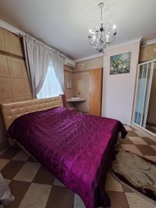 sypialnia z dużym fioletowym łóżkiem z żyrandolem w obiekcie Zatyshok w Czerniowcach