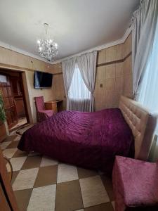 a bedroom with a large purple bed and two chairs at Zatyshok in Chernivtsi