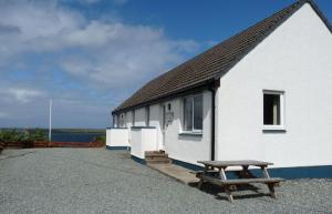a white building with a bench in front of it at Alan's House in Staffin