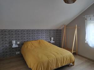 a bedroom with a bed with a yellow blanket at Maison tout confort in La Voivre