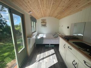a small room with a bed and a sink in it at Cosy Shepherd Huts near Newborough Forest Anglesey in Gaerwen