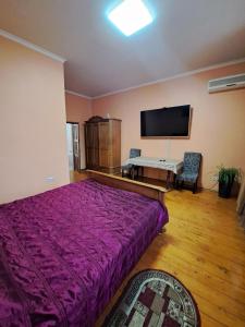 sypialnia z dużym fioletowym łóżkiem i telewizorem z płaskim ekranem w obiekcie Zatyshok w Czerniowcach