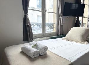 una camera da letto con due asciugamani su un letto con finestra di 1624 - Studio Le Marais in Paris Olympic Games 2024 a Parigi